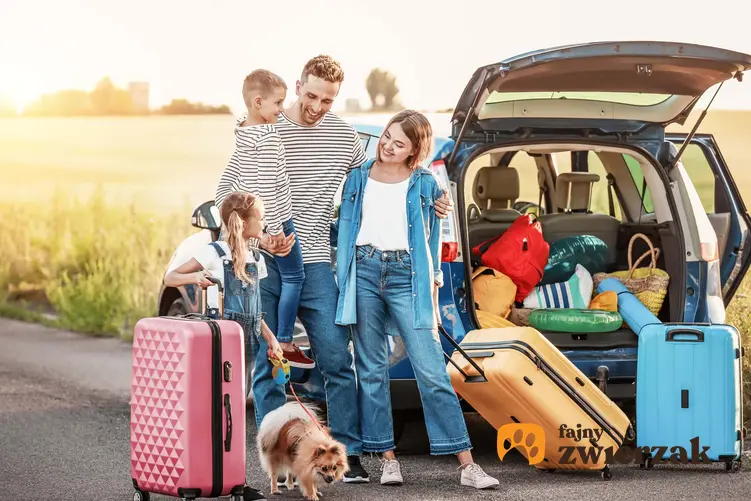 Rodzina z dziećmi i psem stoją przy samochodzie wypełnionym podróżnymi torbami, psiarze na wakacjach, czyli gdzie podróżować z czworonogiem