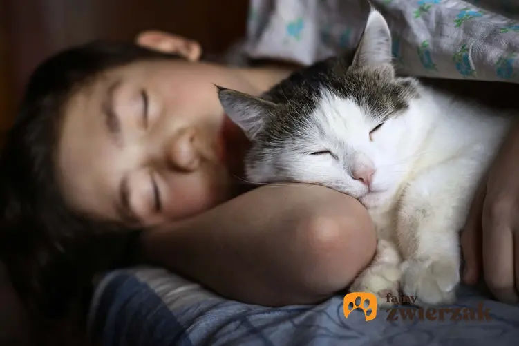 Kobieta przytulona do kota, kot śpiący w nocy przy człowieku, jak oduczyć kota miauczenia bez powodu, koty geriatryczne miauczące w nocy - co jest powodem